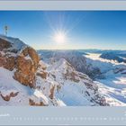Januar 2027. Schneebedeckte Berglandschaft mit strahlender Sonne und einem goldenen Kreuz auf der Spitze.