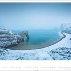 Durdle Door an verschneiter Küste in Dorset, England. Klare blaue Wasserfläche umrahmt von Schnee. Kalender unten.