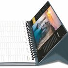 Ein Tischkalender zeigt den 26. bis 31. des Monats. Rechts eine farbenfrohe Strandfotografie bei Sonnenuntergang.