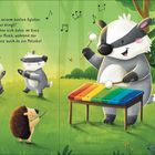 Ein Dachs spielt auf einem bunten Xylophon, umgeben von fröhlichen Dachskindern und einem Igel, in einer Waldszene.