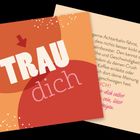 Text: "TRAU dich". Hintergrund in warmen Rot- und Orangetönen mit weißen Punkten.