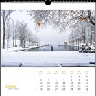 "Januar. Kalender mit schneebedeckten Bäumen und einem ruhigen, vereisten Flussufer unter einem grauen Himmel."