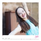 "Juli" steht unten rechts. Kalender zeigt Juli mit Daten. Junge Frau lächelt, trägt blaues Kleid, hebt einen Arm.