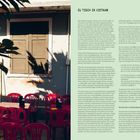 „ZU TISCH IN VIETNAM“: Ein gemütlicher Außenbereich mit roten Plastikstühlen um einen Tisch, Schatten spielen an der Wand.