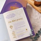 „Du bist genug.“ Ein offenes Buch mit spirituellen Texten und Mantra, umgeben von gemütlichen Elementen wie Strick und Kerzen.