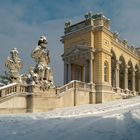 Ein gelbes Gebäude mit Säulen und Statuen, alles von einer Schneeschicht bedeckt.