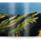 Kein Text sichtbar. Luftaufnahme eines Golfplatzes an einer Küste mit grünen Fairways und umgebenden Klippen.