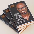 "BIN DA, WER NOCH?" Ein Buchstapel mit einem lachenden Mann auf dem Cover. Autor: Yared Dibaba.