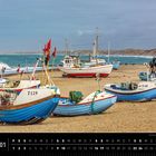 "Dänemark", "01", "Fischerboote am Strand von Vorupør". Boote liegen auf einem sandigen Strand vor einem welligen Meer.