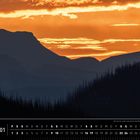 Kalenderblatt: "Kanada 01". Text: "Die Sonne sinkt und taucht die Rockies in goldenes Schweigen." Silhouette von Bergen bei Sonnenuntergang.