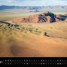 Kalender für Namibia im Januar. Weitläufige Wüstenlandschaft mit Hügeln und Bergen im Hintergrund, blauer Himmel.