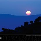 "Andalusien 01", Kalender mit Januar in Wochen. Sonnenuntergang über Bergen, Bäume silhouettiert vor blauem Himmel.