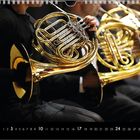 Kalendarium mit markierten Samstagen und Sonntagen. Musiker spielen goldene Hörner.
