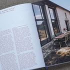 Links steht der Text: "Most of them probably did not expect us to last very long." Rechts ein modernes Gebäude mit Terrasse und Tisch.