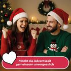 „Macht die Adventszeit gemeinsam unvergesslich.“ Ein Paar in Weihnachtspullovern mit Santa-Mützen. Festlich dekoriert.