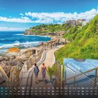 Kalendarium mit „Bondi Beach.“ Küstenweg entlang Felsen und Meer, grünes Gras und moderne Häuser im Hintergrund.