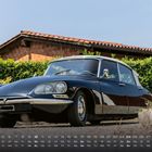 "Citroën DS", Kalenderblätter unten. Schwarzes klassisches Auto vor einem Haus mit Ziegeln, umgeben von Büschen.