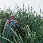 Text: "Kapitel 1", "Schilfzone am Peenetrichter". Ein Mann im Hut steht in hohen Schilfpflanzen und hält eine Kamera.