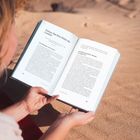 "Füllen Sie Ihre Rolle als Leader", ein geöffnetes Buch auf Sand mit Person, die es hält.