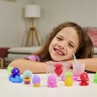 Ein Mädchen lächelt über einen Tisch, der mit bunten Spielzeugfiguren und einer Ananas-Form dekoriert ist. Im Hintergrund ein Sofa.