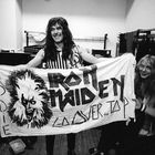 Text: "EDDIE IRON MAIDEN OVER the TOP." Drei lächelnde Personen halten ein Banner mit einem gezeichneten Gesicht darauf.