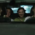 Mehrere Menschen im Auto, sie lachen und wirken fröhlich. Es gibt keine sichtbaren Texte im Bild.