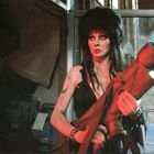 Eine Frau mit schwarzen Haaren und starkem Make-up hält einen großen, roten Gegenstand in ihren Händen.