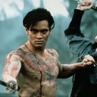 Oben ohne Mann mit tätowiertem Oberkörper und Schwert, kämpft gegen eine schreiende Person mit erhobenem Schwert.