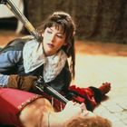 Zwei Personen in historischer Kleidung, eine hält eine Muskete an die Brust der anderen, die am Boden liegt.