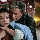 Keine Texte vorhanden. Ein Mann umarmt eine Frau. Beide befinden sich in einem futuristischen, röhrenförmigen Korridor.
