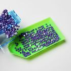 Kleine lila Pailletten auf einem grünen Tablett und daneben ein offener Plastikbeutel mit weiteren Pailletten.