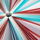 Farbenfrohe Papierfächer, rot und blau, auseinandergefaltet, strahlen symmetrisch von einem zentralen Punkt aus.