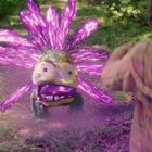 In einem Wald steht eine Figur mit glühenden, lila Blumenblüten und einem offenen Mund. Eine Gestalt schaut ihr zu.