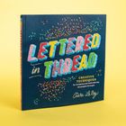 Der Text "LETTERED IN THREAD" erscheint in bunten Buchstaben auf einem dunkelblauen Hintergrund mit gestreuten Farbkonfetti.