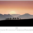 Kalender für den Monat 10; ein Sonnenuntergang mit einer Karawane aus Kamelen vor Bergen.