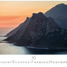 "Chapman's Peak Drive" zeigt eine Küstenansicht mit Bergen bei Sonnenuntergang. Unten sind Monats- und Tageszahlen.