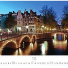 "Abend in der Altstadt" steht dort. Eine beleuchtete Brücke über einem Kanal in einer Altstadt bei Dämmerung.
