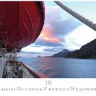 Fjordansicht mit Schiff. Ein Rettungsboot am Schiffsdeck, dahinter ein Fjord mit Bergen und farbigem Himmel. Unten Kalenderzahlen.