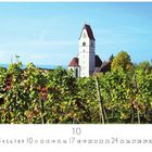 "Kirche in Hagnau", Monatskalender mit Oktober, Weinreben im Vordergrund, Kirche mit Uhr im Hintergrund.