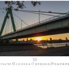 "Severinsbrücke" und "CASARES EDITION" steht unter einer grünen Brücke im Sonnenuntergang. Kalenderdarstellung unten.