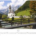 "Ramsau", Kalender mit Oktober-Datum. Kirche vor Alpenpanorama, Bach, Brücke, grüne Wiesen und herbstliche Bäume.