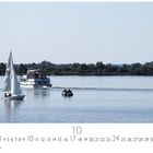 Kalenderblatt mit Zahlen 1-31 und Monat 10. Naturaufnahme: Segelboot, Motorboot und Schlauchboot auf einem See.