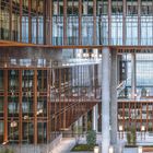 Moderne Architektur mit vielen Glasfassaden, rechteckigen Strukturen und hellen Innenhöfen voller Grünpflanzen.