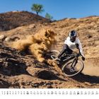 Kalenderblatt mit Datum 10 und Tagen von 1 bis 31. Ein Mountainbiker fährt dynamisch durch sandiges Gelände.