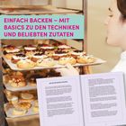 EINFACH BACKEN – MIT BASICS ZU DEN TECHNIKEN UND BELIEBTEN ZUTATEN. Eine Person backt Kekse und liest in einem Buch.