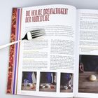 Text: "Die heilige Dreifaltigkeit der Nudelteige." Zwei Buchseiten mit Rezepten, Bildern und Text, rechts liegt eine Gabel.