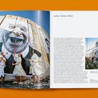 Texte: "28 Millimeters, Women Are Heroes, 2009", "Action in Kibera Slum, general view Nairobi, Kenya". 

Beschreibung: Luftaufnahme von Wellblechdächern mit großen Schwarz-Weiß-Porträts von Gesichtern. Häuser im Hintergrund.