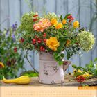 "Oktober" und "GARDEN". Ein rustikaler Krug mit buntem Herbststrauß aus Rosen und Beeren, daneben eine gelb-grüne Zierkürbis.