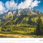 Text: 3.10. Tag der Deutschen Einheit. 
Szene: Malerische Berglandschaft mit grasbewachsenen Hügeln und beeindruckenden Felsgipfeln.