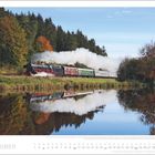 Der Text „OKTOBER“. Darunter eine Dampflokomotive, die an einem Fluss entlangfährt, umgeben von herbstlich gefärbten Bäumen.